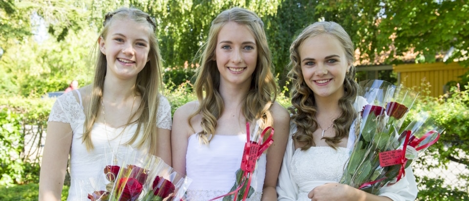 Festfotografen har her fotograferet 3 kvindelige konfirmander, der står opstillet side om side. De holder alle roser i cellofan.